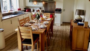 A modern kitchen with wooden cabinets, a dining table set for six, and a built-in oven.
