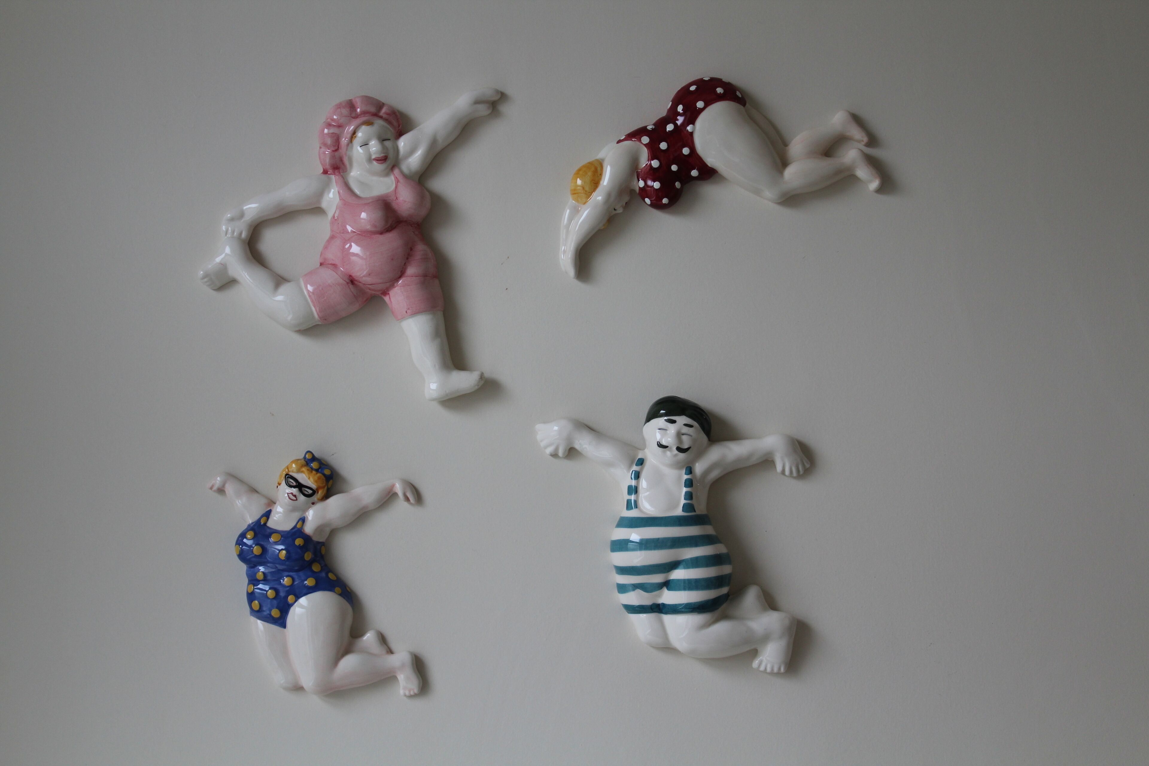 Cuatro figuritas de cerámica en diferentes poses y atuendos.