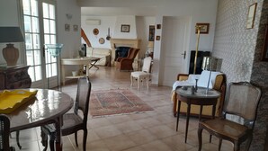 A spacious living room with a dining area, a fireplace, and a large window.