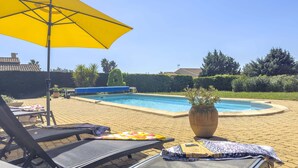 A poolside area with lounge chairs, a yellow umbrella, and a potted plant.