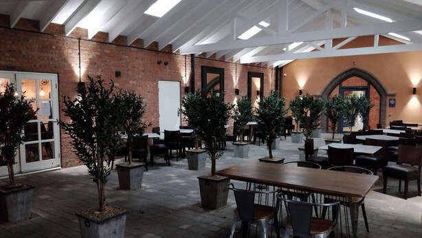 An indoor dining area with brick walls, wooden tables, and chairs. There are potted plants and a whiteboard on the wall. - Filey. Active leisure or relaxing beach holiday. (Filey)