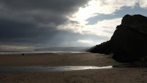 A beach with a rocky outcrop and a cloudy sky. - Filey. Active leisure or relaxing beach holiday. (Filey)
