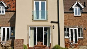 A two-story house with a front patio, a dining area with wooden furniture, and a garage door. - Filey. Active leisure or relaxing beach holiday. (Filey)