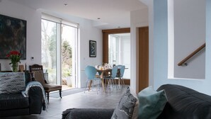 Ein modernes Wohnzimmer mit einer Couch, einem Essbereich mit Stühlen und einer Treppe.