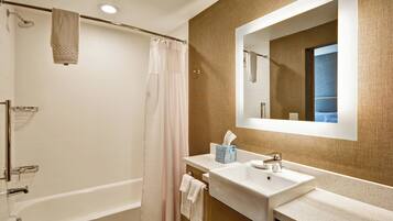 A modern bathroom with a bathtub, a shower, a sink, and a mirror.