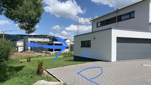 A modern building with a garage, a paved driveway, and a grassy area with a large rock. - New apartment in a quiet location in the recreation area (Schömberg)