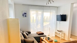 A modern living room with a sofa, a coffee table, and a TV mounted on the wall. - New apartment in a quiet location in the recreation area (Schömberg)
