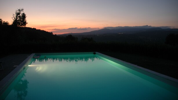 Une piscine offrant une vue sur les montagnes lointaines au crépuscule.