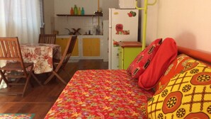 Une chambre avec un lit, une table à manger, des chaises et un coin cuisine.