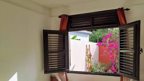 Une chambre à coucher avec un lit, un ventilateur de plafond et une fenêtre dont les volets sont ouverts.