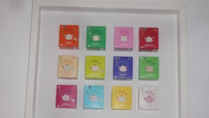 Une collection de boîtes de thé de la marque English Tea Shop, présentées dans des cadres et proposant différentes saveurs.