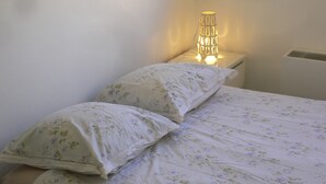 Un lit avec une literie à motifs floraux et deux oreillers, une lampe de chevet et un radiateur.