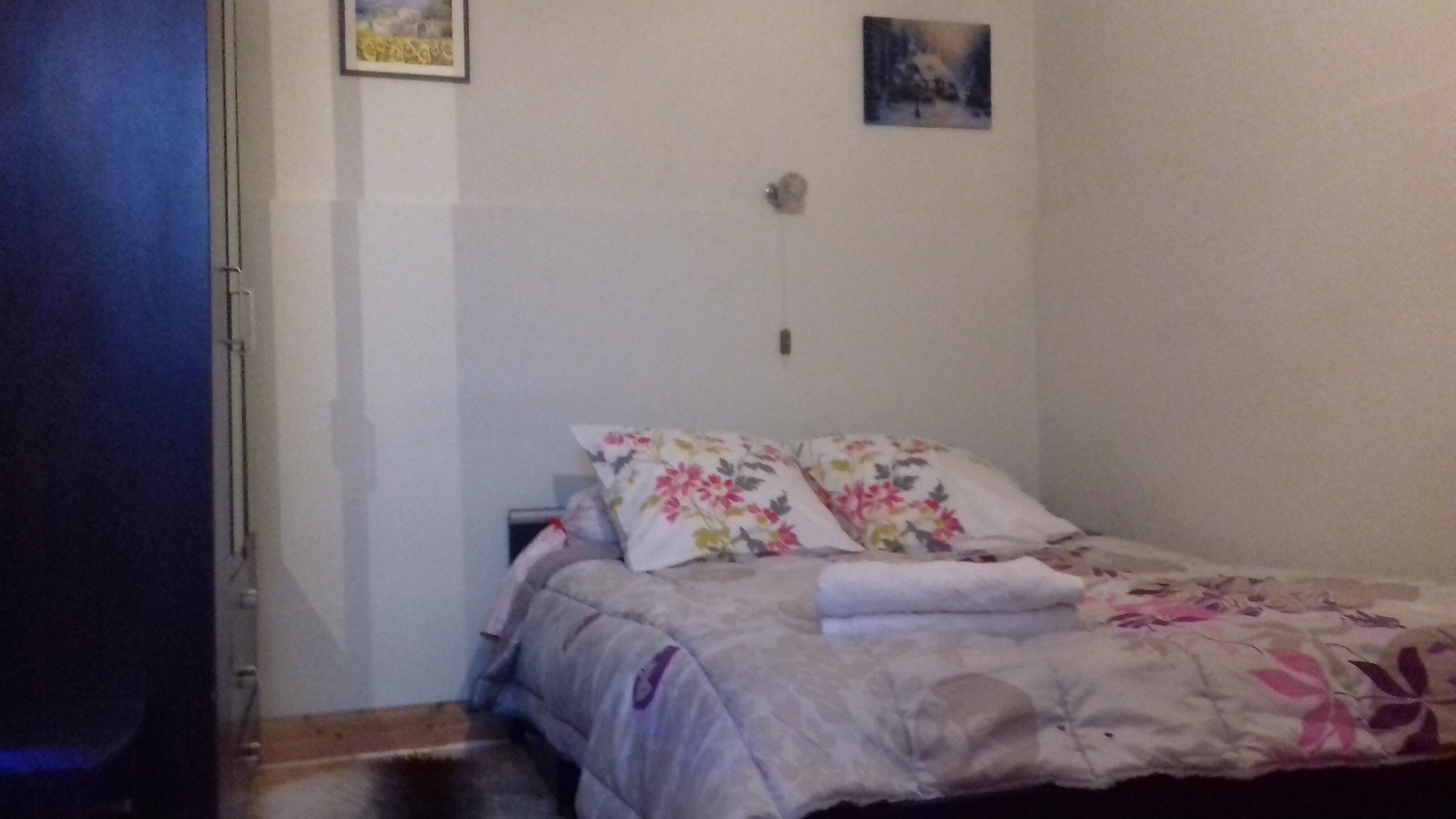 Un dormitorio con cama, mesita de noche y lámpara de pared.