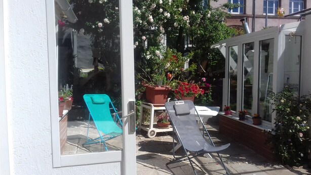 A patio area with two lounge chairs, a small table, and potted plants. - Comme chez vous prés sur la route des vins! (Mutzig)