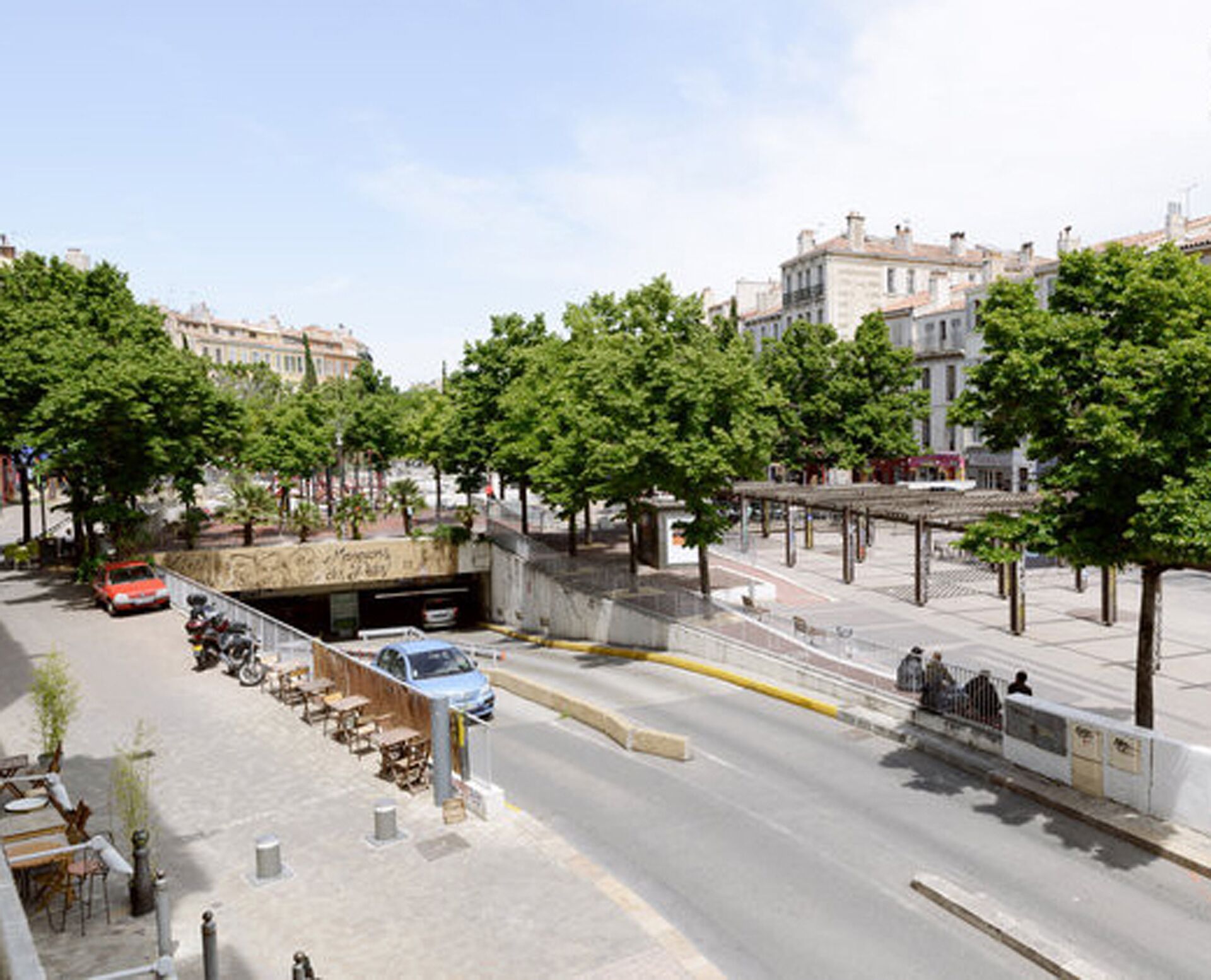 A street view with a pedestrian bridge, trees, and buildings.