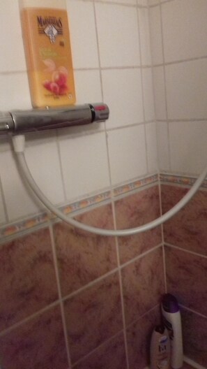 A bathroom with a shower, a towel rack, and a bottle of shampoo.