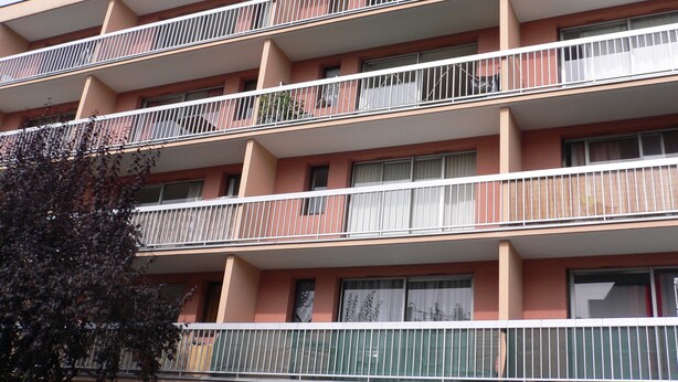 A multi-story residential building with balconies, each with metal railings. - Lush greenery in the city center (Rouen)