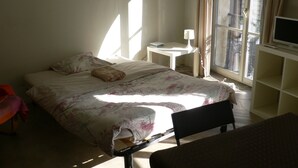 A bedroom with a bed, a bedside table, a chair, and a TV. - Historic center - Old market (Rouen)