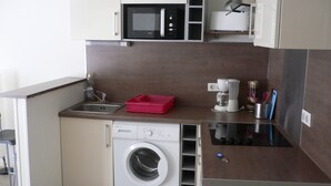 A compact kitchen with a washing machine, a microwave, and a coffee maker. - Historic center - Old market (Rouen)
