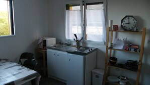 Una cucina compatta con lavandino, fornelli e un orologio appeso al muro.