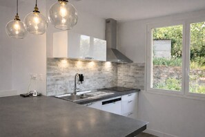 A modern kitchen with a large island, stainless steel appliances, and a window with a view of greenery.