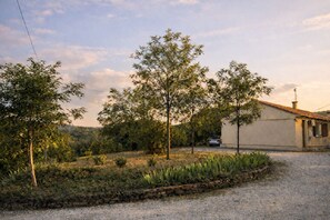A rural property with a gravel driveway, a single-story building, and a car parked in the background.