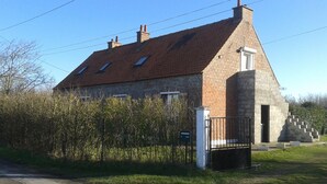 Ein zweistöckiges Steinhaus mit geneigtem Dach, einem verschlossenen Eingang und einer Treppe, die zu der oberen Etage führt.
