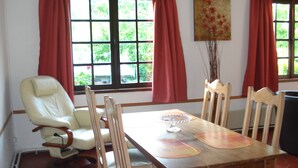 Un comedor con mesa de madera, sillas y ventana con cortinas.