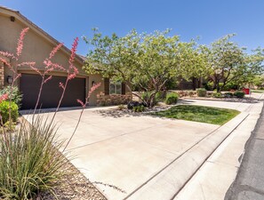 A residential driveway with a garage, a lawn, and a small tree.