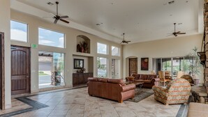 A spacious lobby with a brown leather sofa, a patterned armchair, and a stone fireplace.