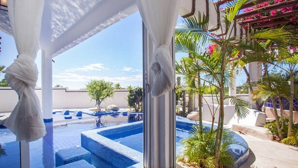 A pool area with steps leading into the water, surrounded by palm trees and a pergola with flowers. - BEAUTIFUL VILLA WITH PRIVATE POOL (Cabo San Lucas)
