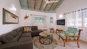 Una sala de estar con sofá, sillón, mesa de centro redonda y ventilador de techo.