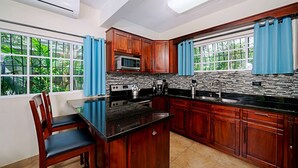 Una cucina con mobili in legno, un piano di lavoro nero, un forno a microonde, un fornello e un lavandino.