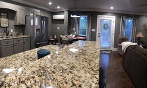 A modern kitchen with granite countertops, a stainless steel refrigerator, and a dining area with a table and chairs. - NO PETS. fully furnished, sleeps four. Beautiful retreat and close to town. (Corinth)
