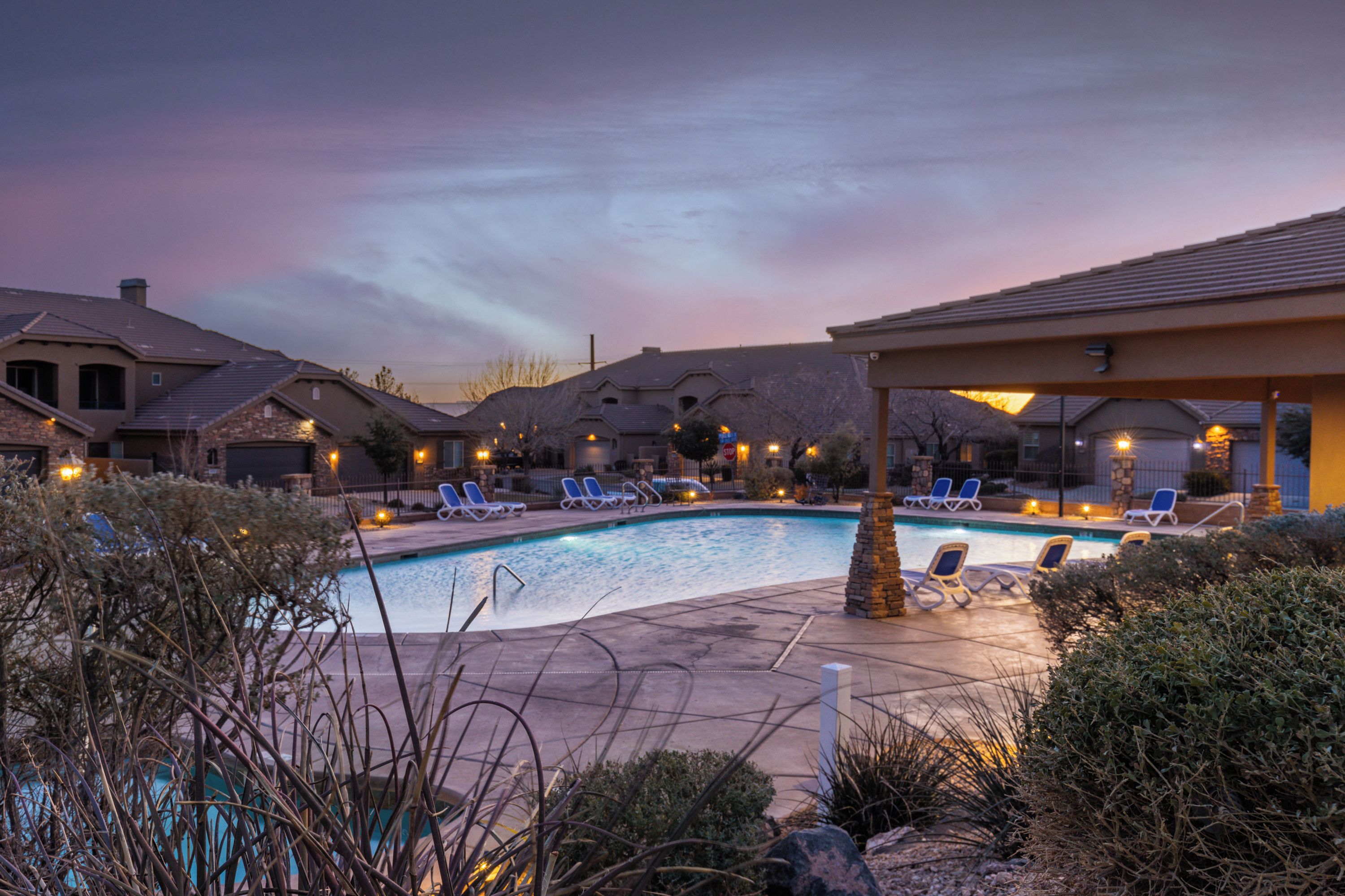 A swimming pool area with lounge chairs and a covered seating area.