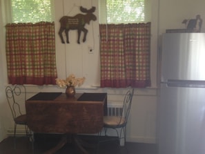 Cozy dining area with a wooden table, vase of flowers, and refrigerator.