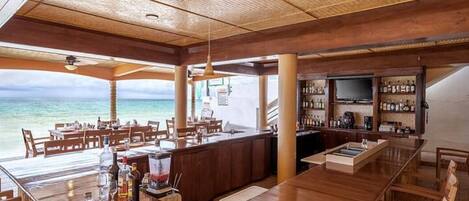 A bar area with wooden furniture, a television, and a view of the ocean.