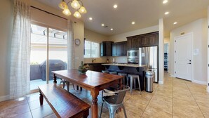 A modern kitchen with dark cabinets, stainless steel appliances, and a wooden dining table.