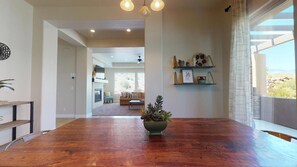 A spacious dining area with a wooden table, a potted plant, and a view of a living room with a sofa and a fireplace. - Zion's Getaway  2 Pools and Hot tub! (Washington)