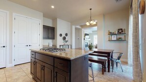 A modern kitchen with dark cabinetry, a granite countertop, and a dining area with a wooden table and chairs.