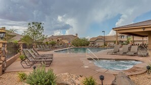A pool area with lounge chairs and a hot tub, surrounded by stone walls and houses. - Zion's Getaway  2 Pools and Hot tub! (Washington)