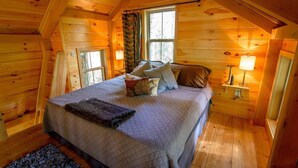 A cozy wooden cabin bedroom with a bed, pillows, a nightstand, and a window. - Stay in Tree House built by TreeHouse Master Pete Nelson ~ off the grid (Germantown)
