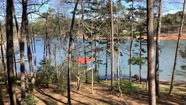 Une zone boisée avec un lac, un quai et un bâtiment au toit rouge.