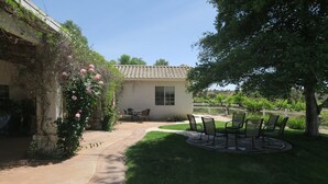 Un patio con un edificio pequeño, mobiliario exterior y un jardín.