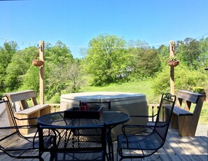 Eine Terrasse im Freien mit einem runden Tisch, Stühlen, einem Whirlpool und Holzbanken.
