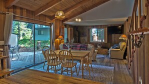 A cozy wooden interior with a dining area, sofa, and TV. - The Lyons Den at Upper Timberline Village (Packwood)