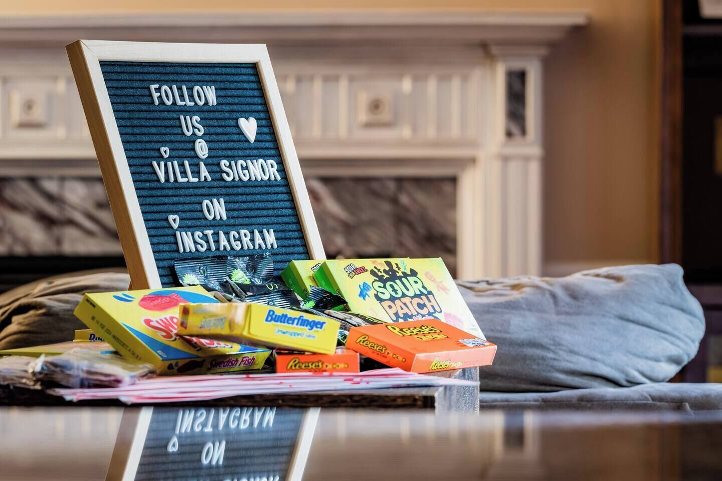A sign with a message to follow a villa on Instagram, placed on a table with various candy boxes.