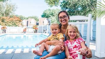 Family enjoys a relaxing moment by the pool surrounded by lush greenery.