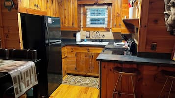 Une cuisine de style rustique, avec des éléments en bois, comprenant un réfrigérateur, un évier et des tabourets de bar.