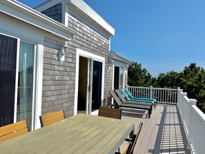 A deck with a table and chairs, a sliding glass door, and a white railing. - New for 2026- the perfect family getaway (Wellfleet)